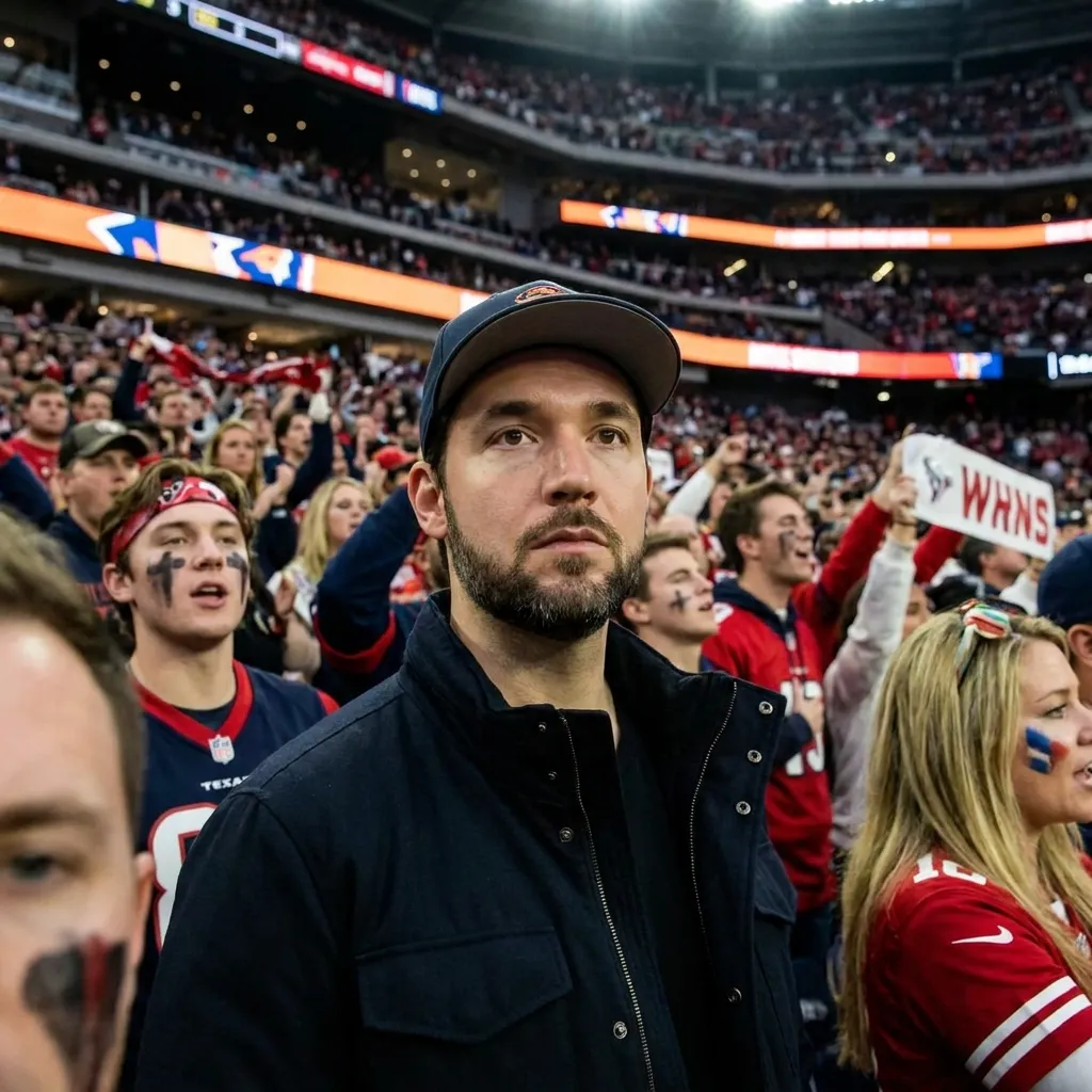 Alexis Ohanian looking serious in a busy stadium crowd surrounded by cheering sports fans wearing team apparel.