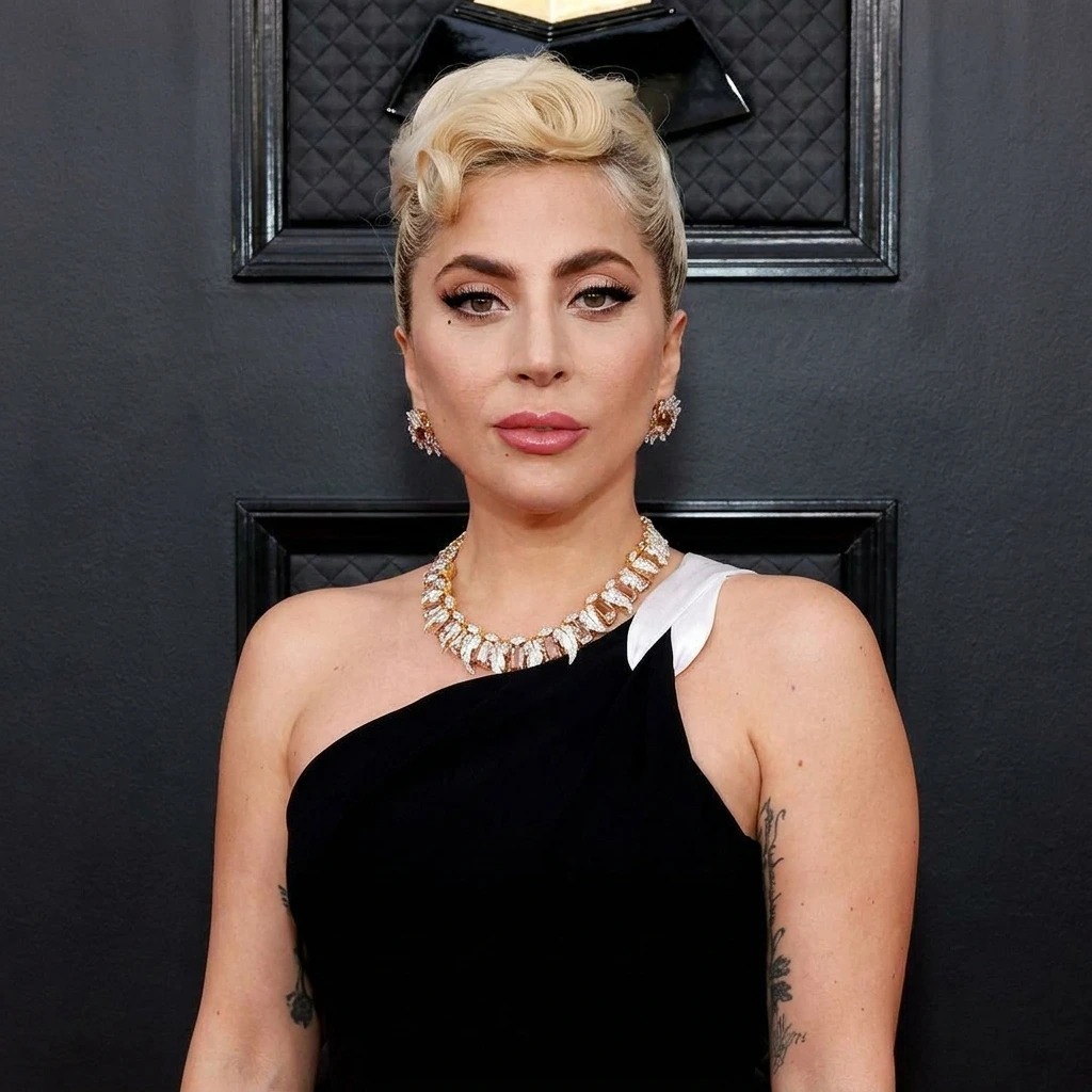 Lady Gaga posing on the Grammy Awards red carpet in a black one-shoulder dress, statement diamond necklace, and vintage blonde updo.