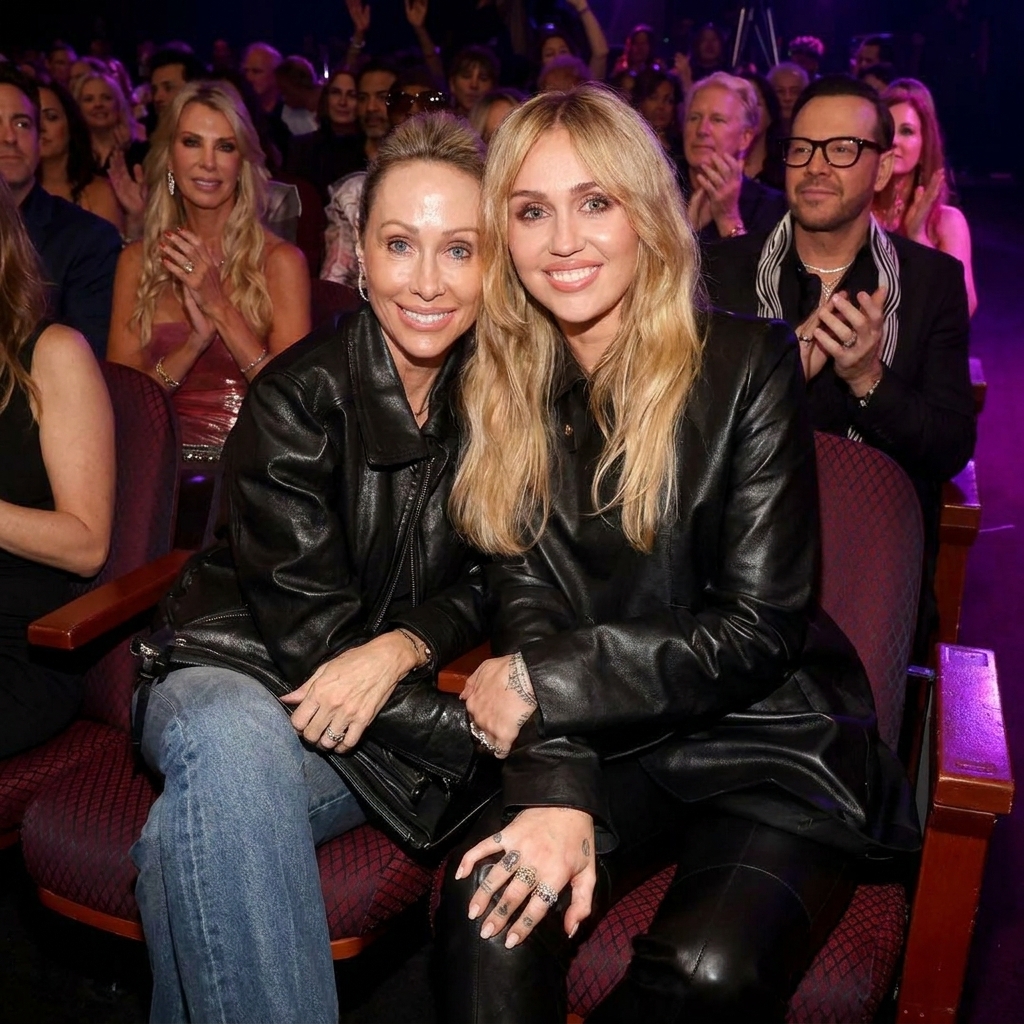 Miley Cyrus and Tish Cyrus sitting together in the audience wearing black leather jackets at an entertainment event
