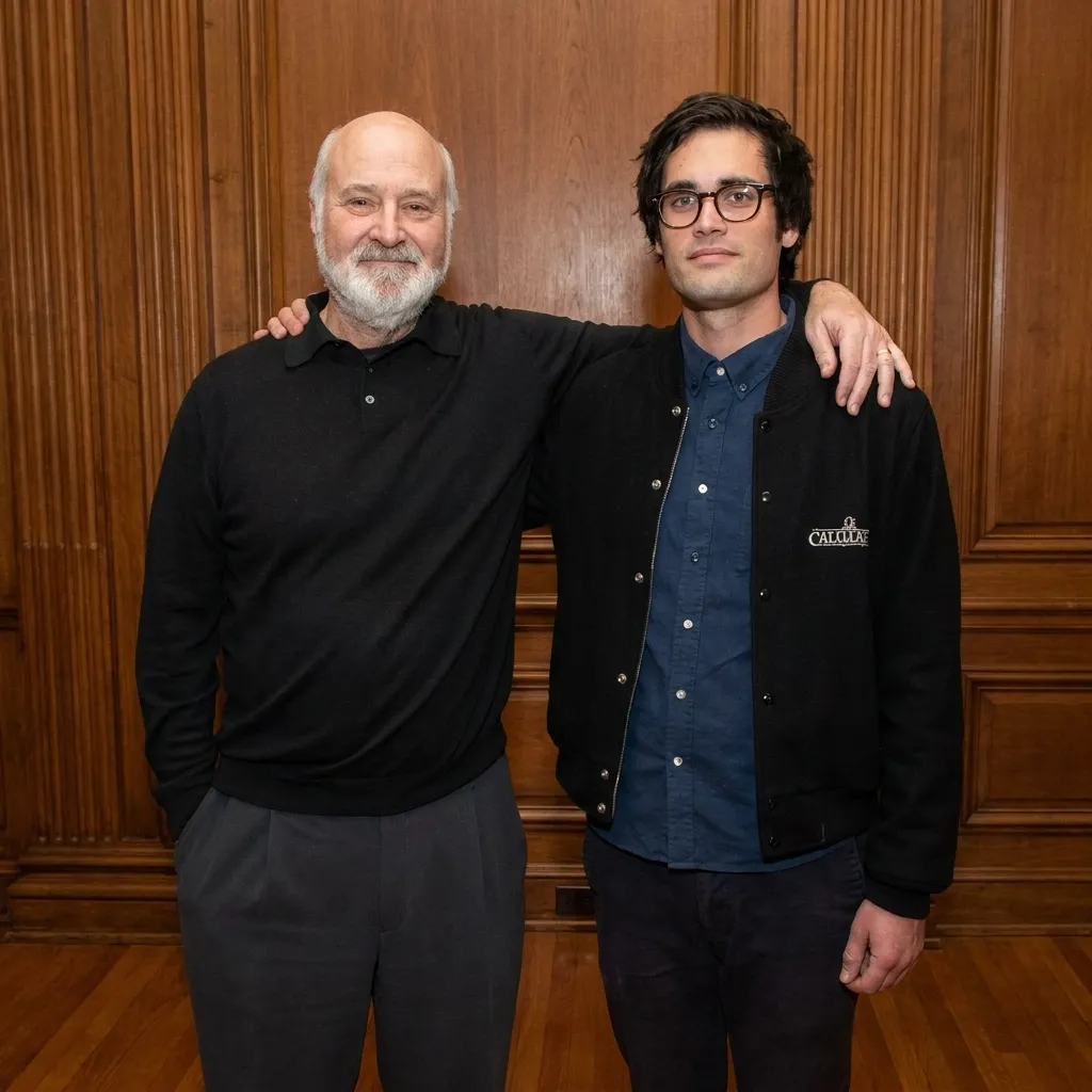 Portrait of director Rob Reiner standing with his arm around a younger man against a classic wood-paneled wall.