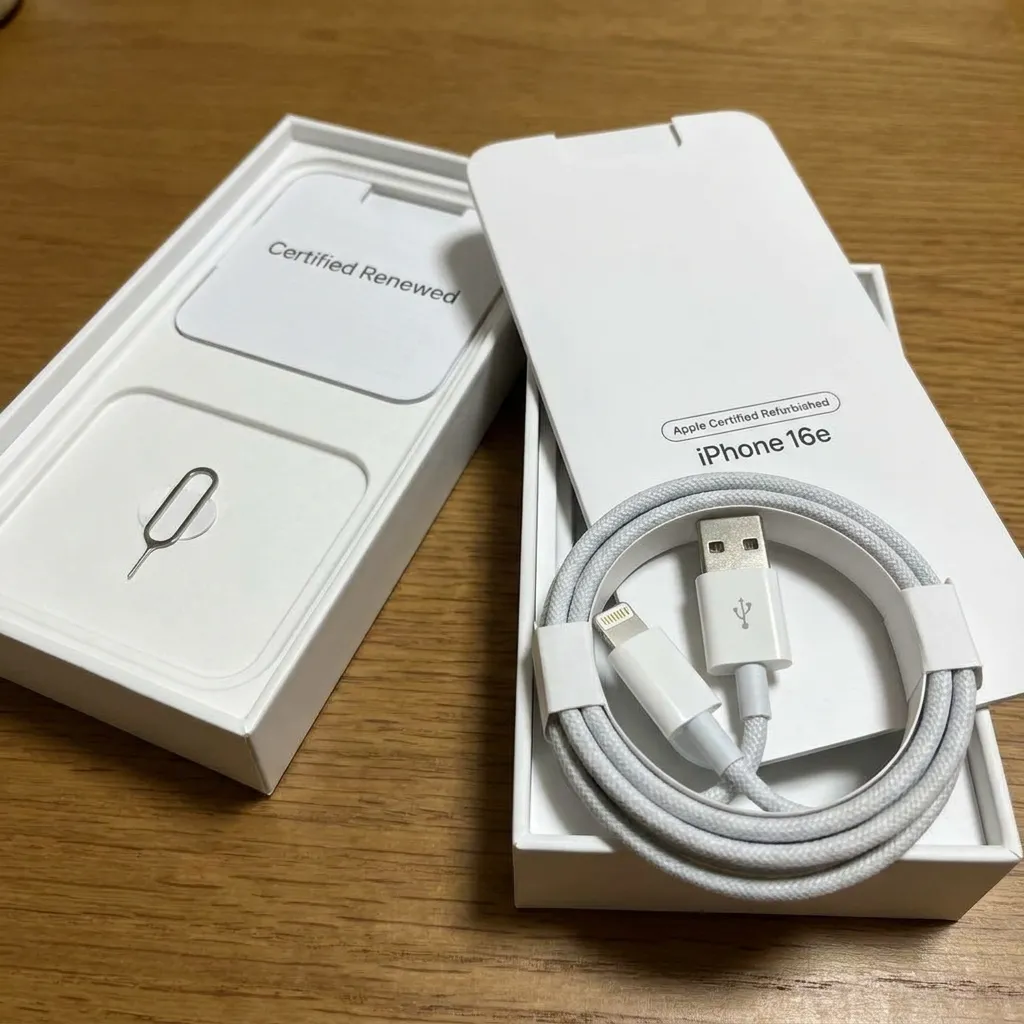 A close-up view of a certified renewed device box and original charging cables, highlighting the complete unboxing experience of official refurbished iPhone 16e deals.