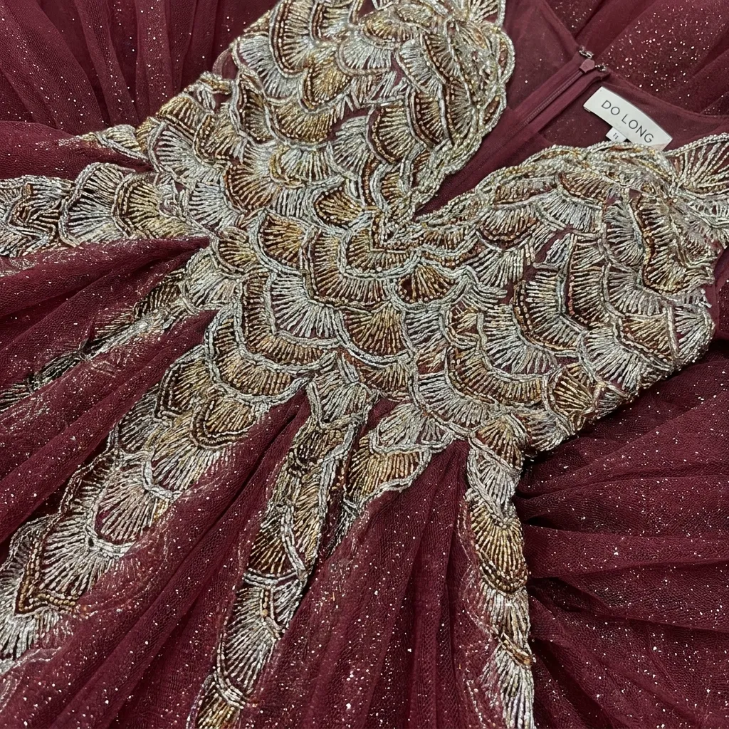 Close-up of the shimmering metallic detailing and burgundy tulle on Simone Biles's custom DO LONG designer gown.