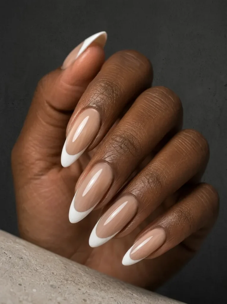 Almond-shaped nails styled with a classic sheer nude base and crisp white French tips