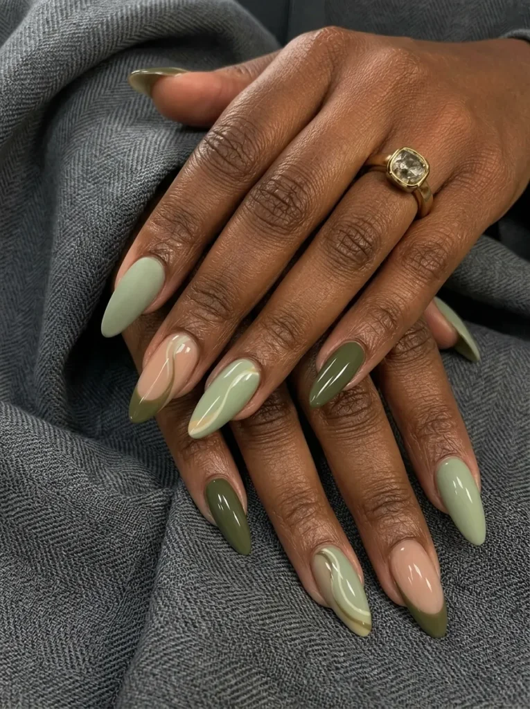Almond-shaped nails showcasing a mix of sage green, deep olive, and neutral abstract swirls and French tips