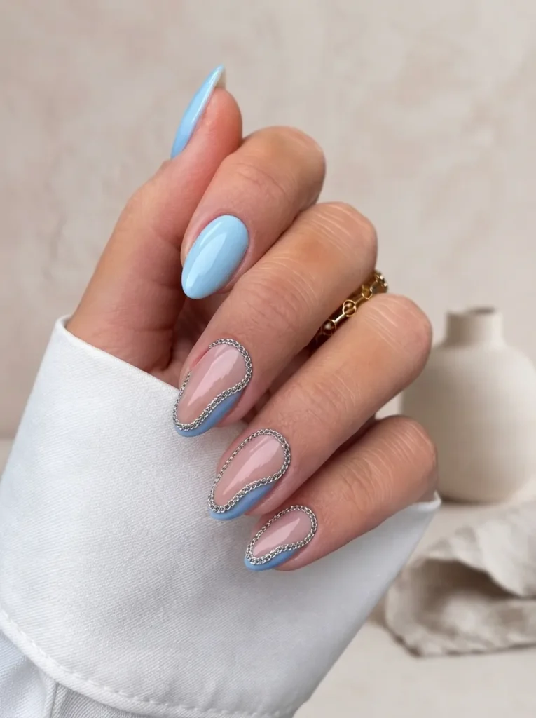 Almond-shaped nails with light blue polish and silver chain outline art