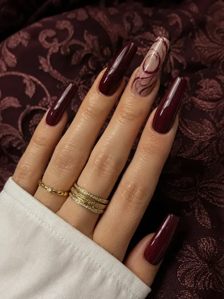Burgundy coffin nails featuring a swirl accent art design on a textured background.