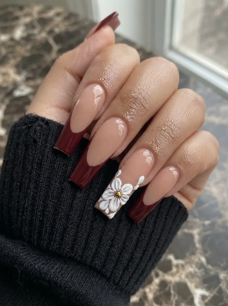 Burgundy french manicure featuring a white 3D floral accent nail on a long coffin shape.