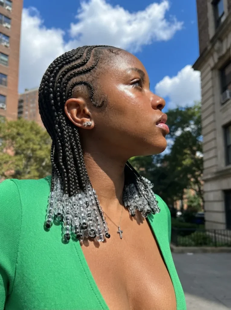 A woman with curved cornrows adorned with clear beads at the ends