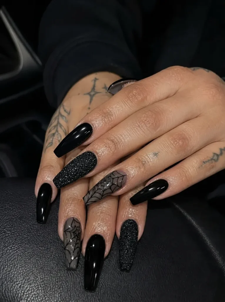 Long coffin nails showcasing a mix of glossy solid black, heavily textured black glitter, and matte black nails with detailed spiderweb patterns.