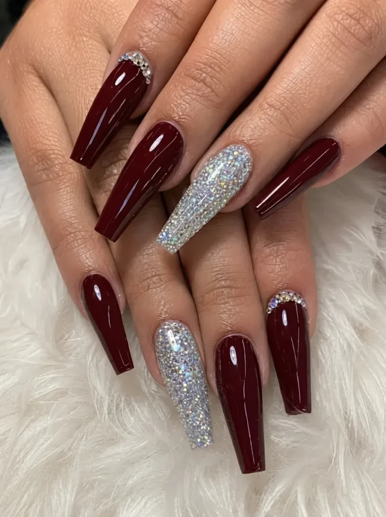 Glossy burgundy coffin nails styled with full silver glitter feature nails and rhinestone cuticle accents.