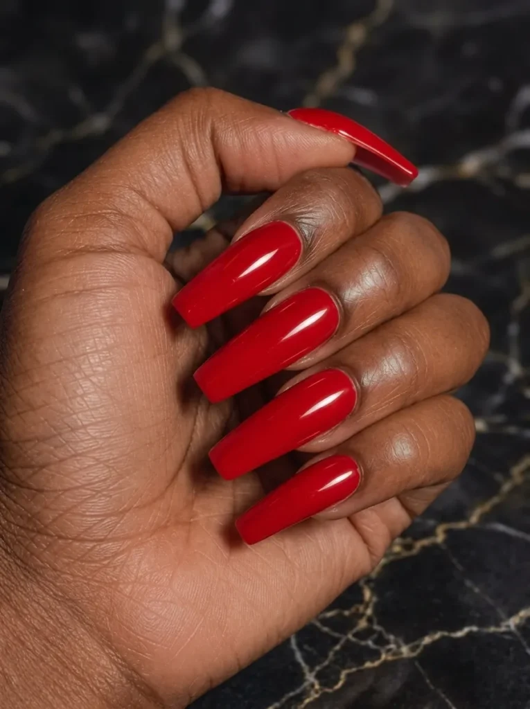 Long coffin-shaped nails painted in a solid, high-gloss classic bright red color