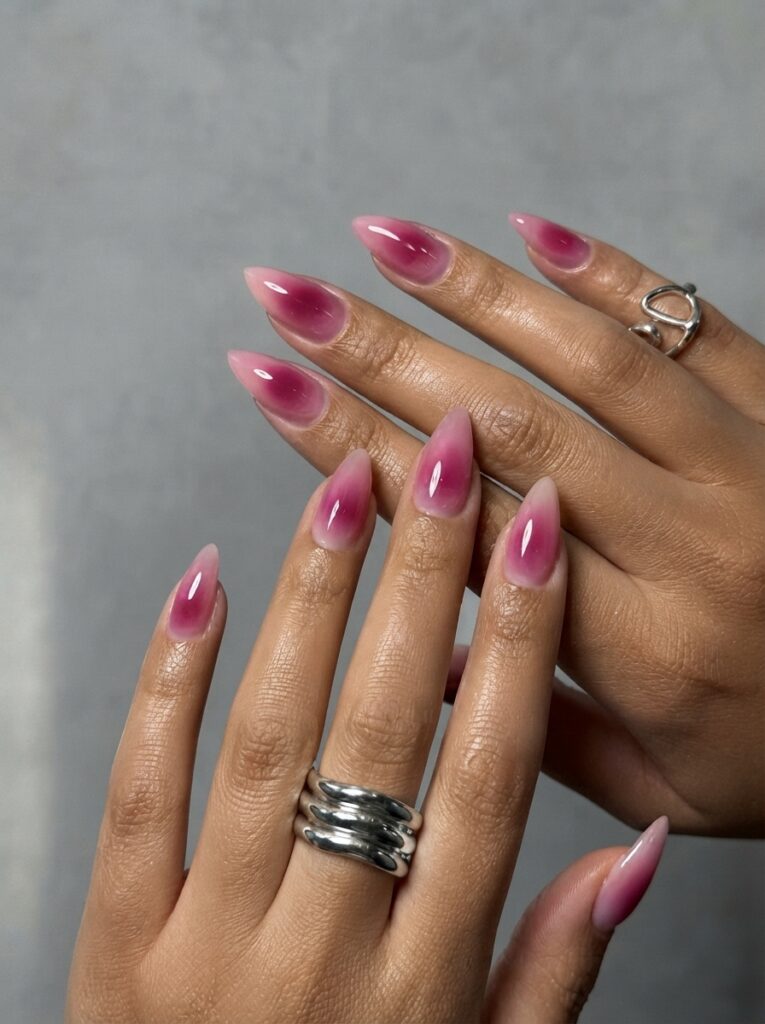 Hands showing magenta pink aura almond nails styled with chunky silver rings