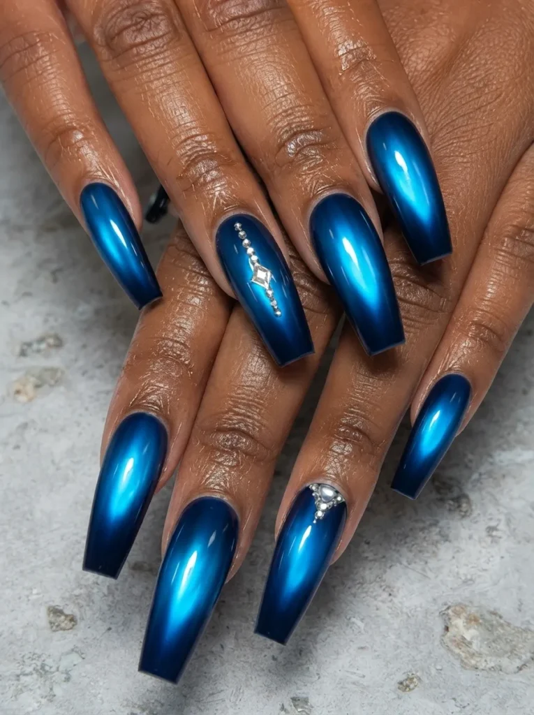 Hands displaying metallic blue cat-eye coffin-shaped nails accented with delicate rhinestones
