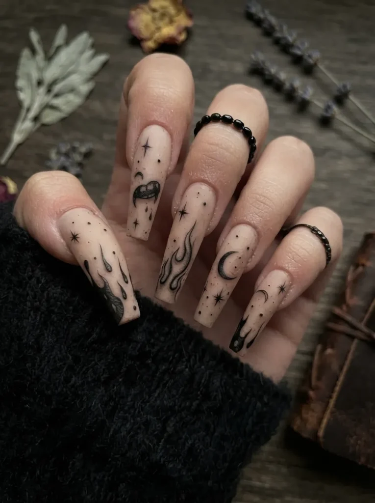 Long coffin nails with a neutral beige base featuring minimalist tattoo-style black line art of flames, crescent moons, stars, and mystic symbols.