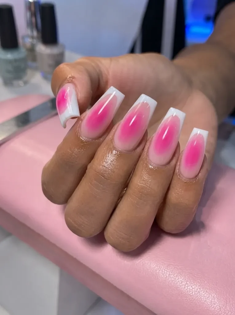 Hand with square-shaped nails featuring white French tips and pink aura gel design