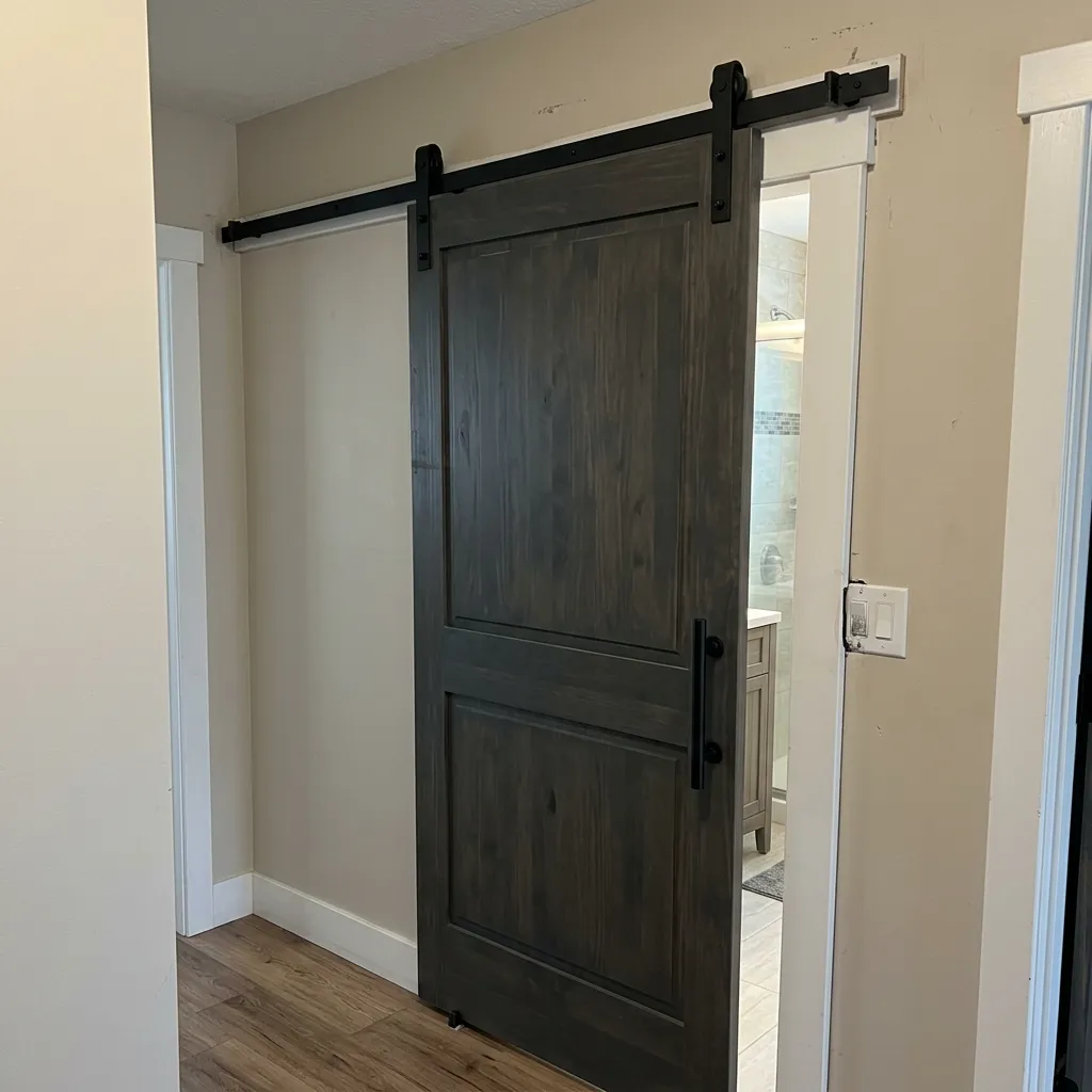 Dark stain wood sliding barn door mounted on black hardware leading into a bathroom.